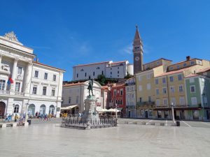 Wo heute der Tartini-Platz liegt, war früher ein Fischerhafen. Der Platz ist der zentrale Ort von Piran; zahlreiche schmucke Häuser und Palazzi bilden das passende Ambiente; er wird dominiert vom Gemeindepalast (links) und der auf einem Hügel stehenden Kirche St. Georg. – Foto: Dieter War