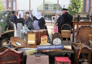 Das sind nicht lauter Frau Antjes, die den Schagener Markt besuchen, um den Käseverkauf anzukurbeln. Die Werbefigur Frau Antje wurde auf der Grünen Woche in Berlin 1959 entwickelt, um für holländischen Käse zu werben. Diese Damen tragen kein langes blondes Haar mehr, aber sie tragen die Volendamer Haube, die typisch geworden ist für die Werbefigur