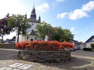 Hallenberg ist die kleinste westfälische Gemeinde sowie die zweitkleinste Stadt von Nordrhein-Westfalen. Am Südrand des Marktplatzes des historischen Fachwerkstädtchen bildet der Petrusbrunnen einen optischen Kontrapunkt zur St.-Heribert-Kirche, deren Entstehung ins 13. Jahrhundert zurückreicht. – Foto: Dieter Warnick