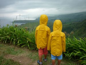 Blick auf die Küste: Kinder mit Regenmantel.