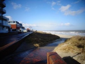Die Wangerooger Strandpromenade besteht aus einer Oberen und einer Unteren Promenade, die entlang des Badestrandes verläuft und ein Zentrum des Insellebens darstellt. Hier können Besucher entlang flanieren, die Aussicht auf die Nordsee genießen und romantische Momente erleben. Die Promenade ist Teil der Fußgängerzonen von Wangerooge und bietet Restaurants und Cafés. – Foto: Dieter Warnick