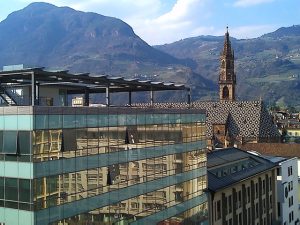 Bozen ist auch eine Stadt der Gegensätze: Blick von der Dachterrasse des Hotels Falkensteiner auf das gegenüberliegende moderne Glasensemble und den gotischen Dom Maria Himmelfahrt am Waltherplatz. – Foto: Dieter Warnick