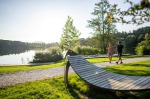 Die Pause naht, die Holzliege steht bereit: Zwei Wanderer am Ufer des Maltschacher Sees. – Foto: Gert Perauer